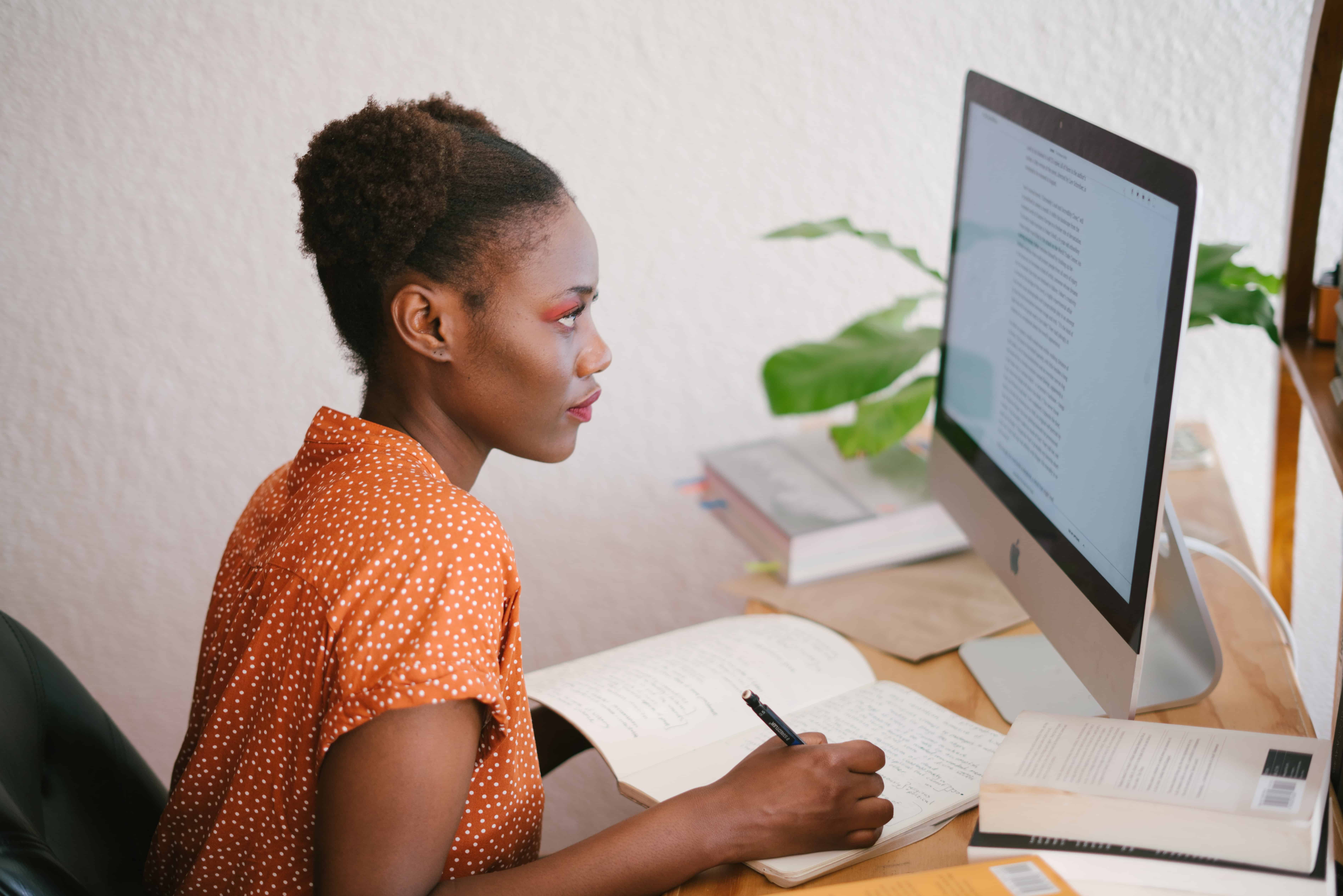 Woman working on computer and note book.